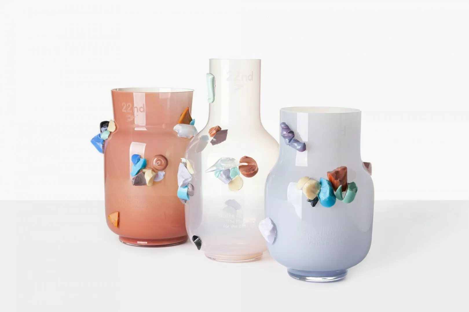 Three colorful glass vases with decorative stones.