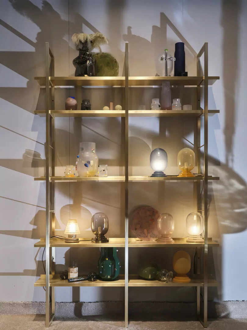 Wooden shelves displaying various artistic glass objects.