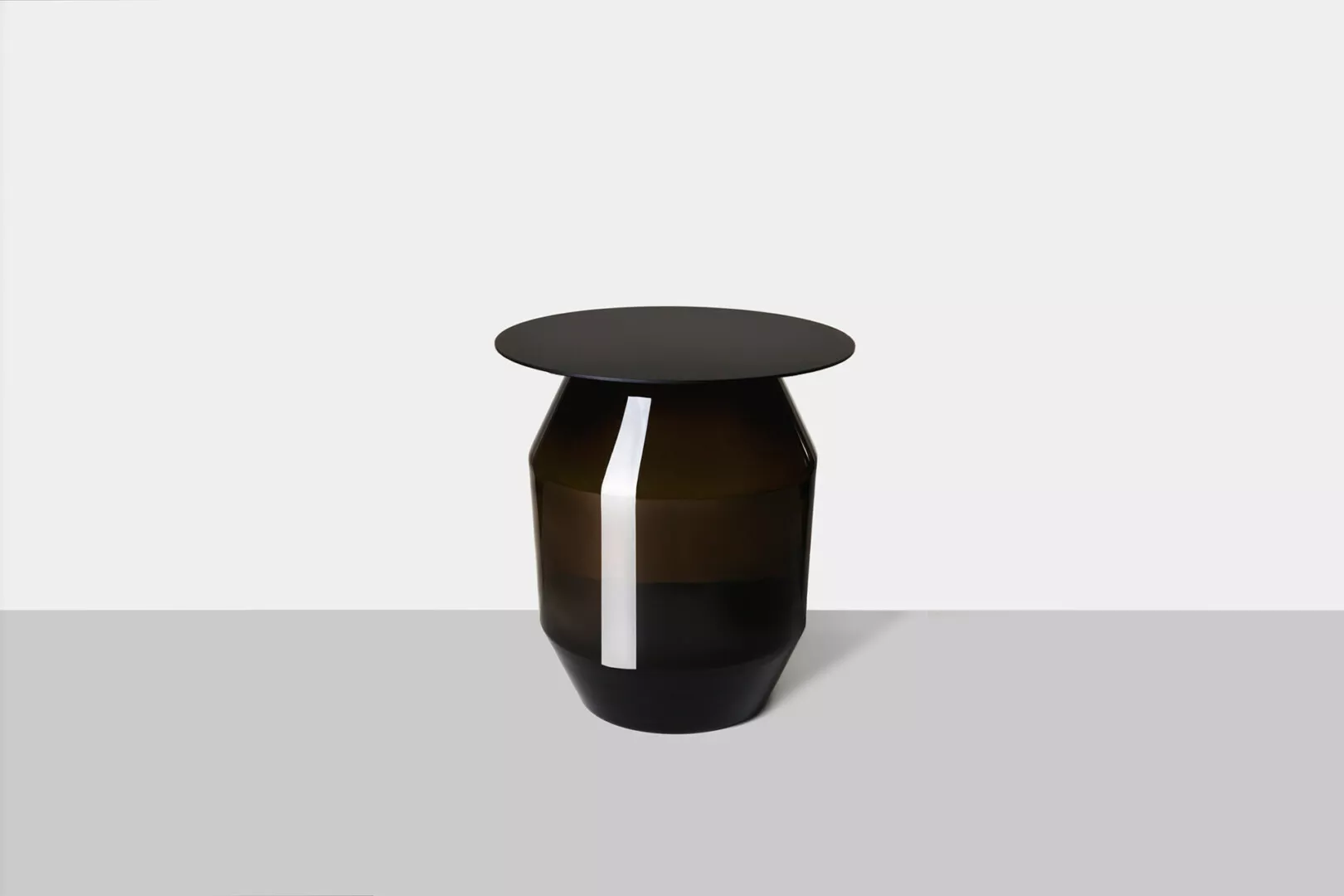 Modern black vase with vertical white stripe on gray background.