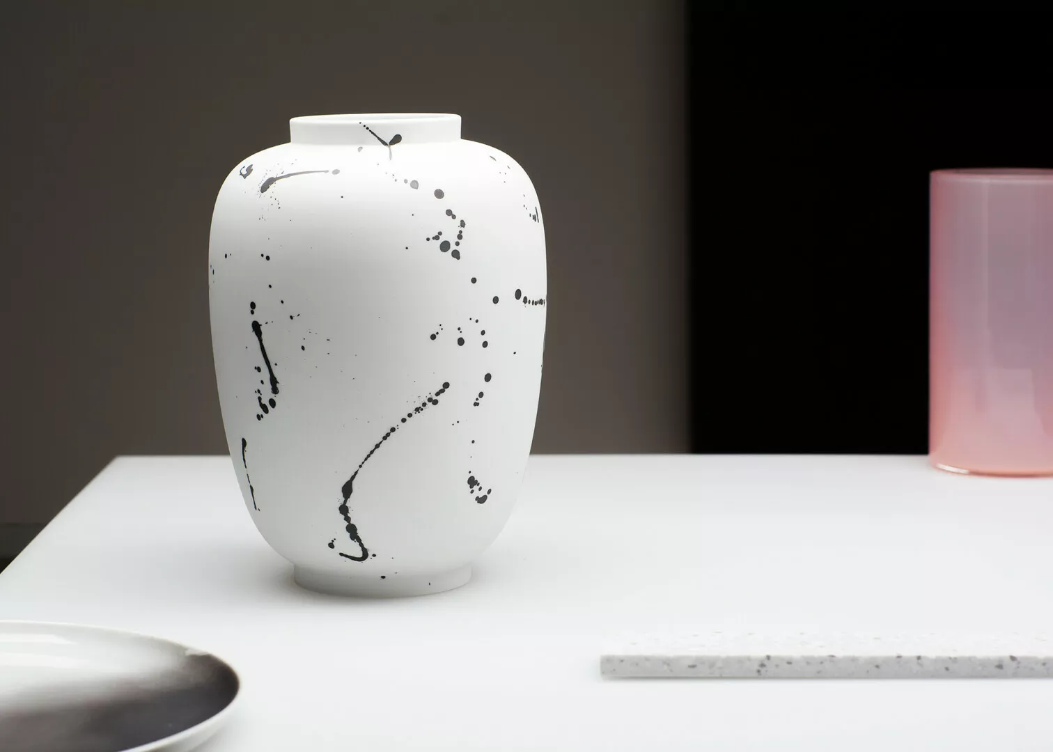 White splattered vase on modern minimalist table.