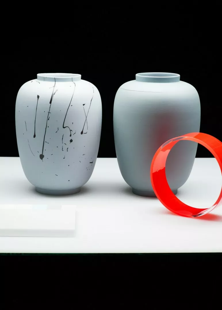 Two ceramic vases and red translucent ring on black.