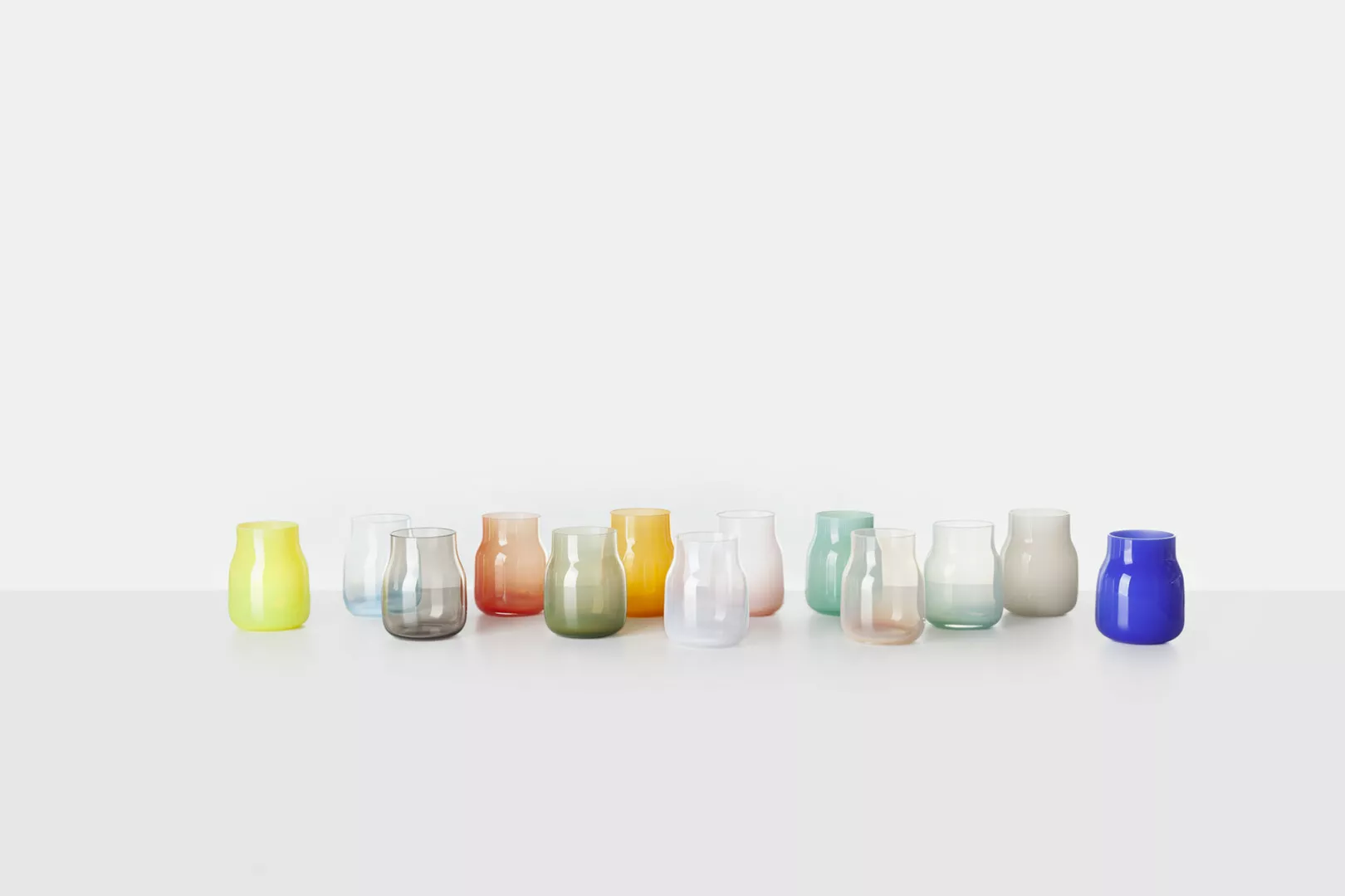 Colorful glass vases line on white background.