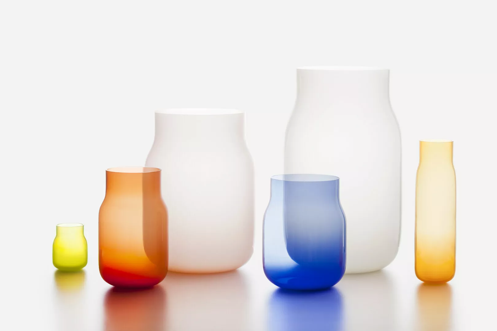 Assorted colorful glass vases on white background.