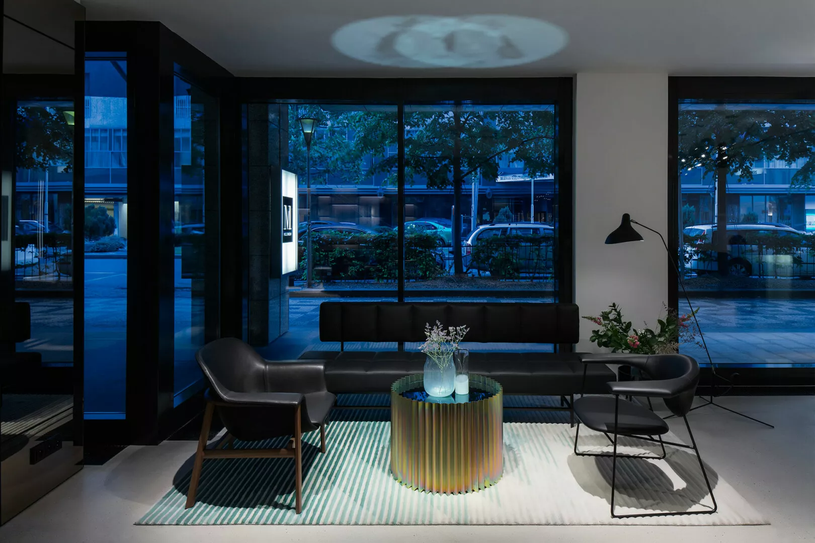 Modern lobby with stylish furniture and large windows at dusk.