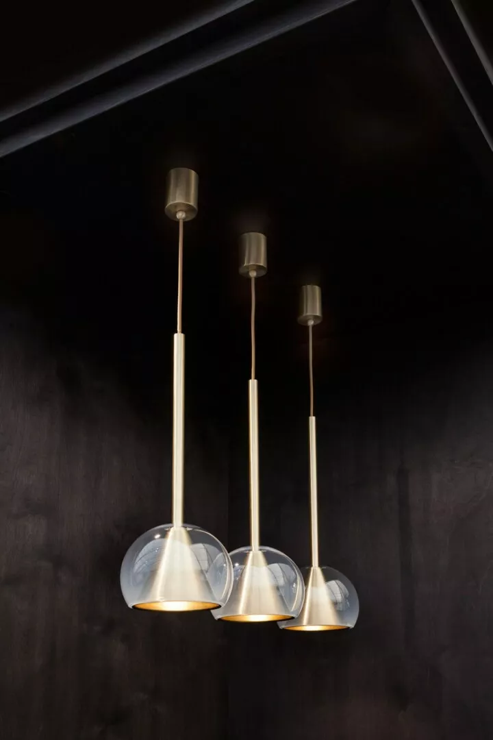 Three elegant pendant lights against dark background.