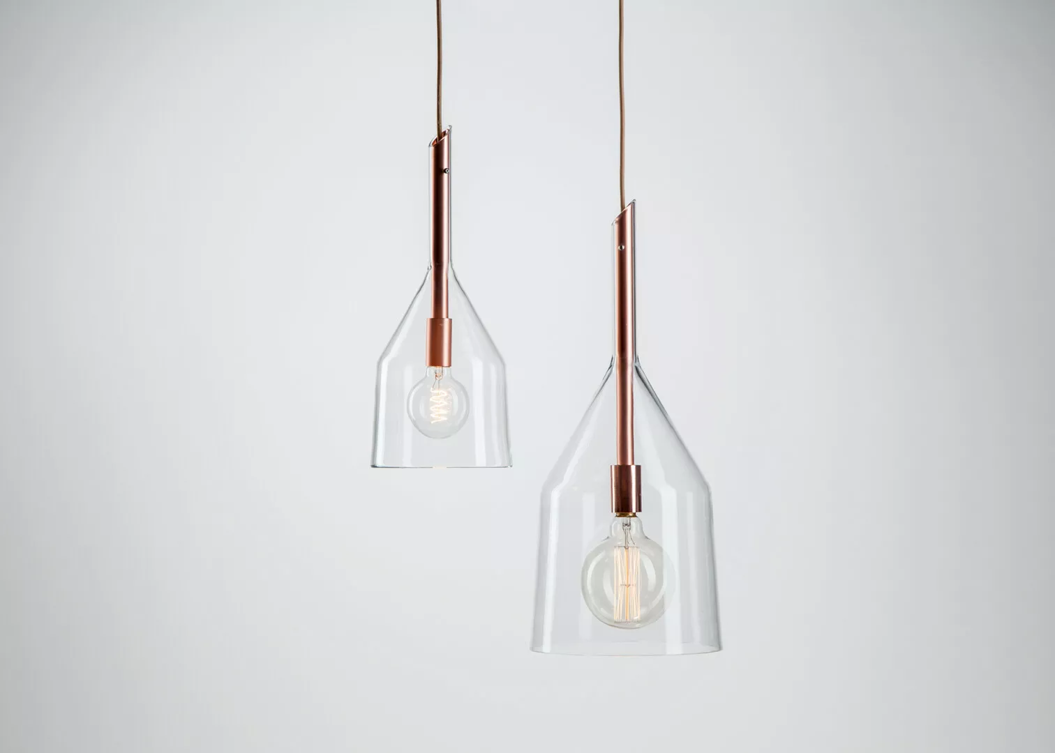 Modern glass pendant lights with copper fixtures.