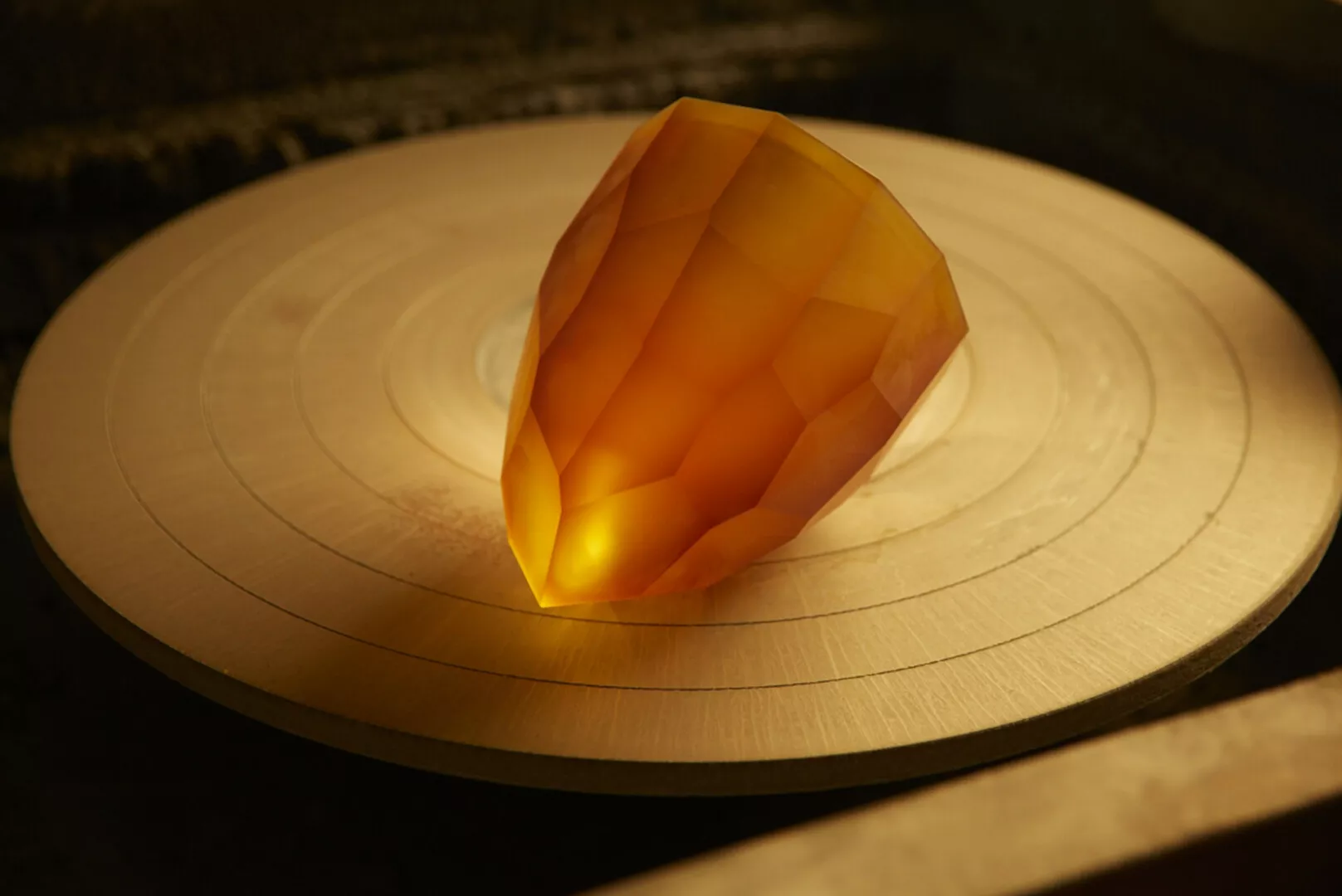 Illuminated orange gemstone on wooden surface.