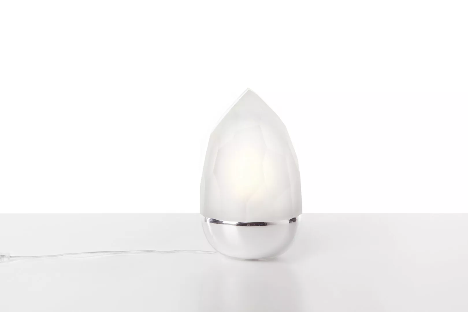 Modern white teardrop-shaped table lamp on white background.