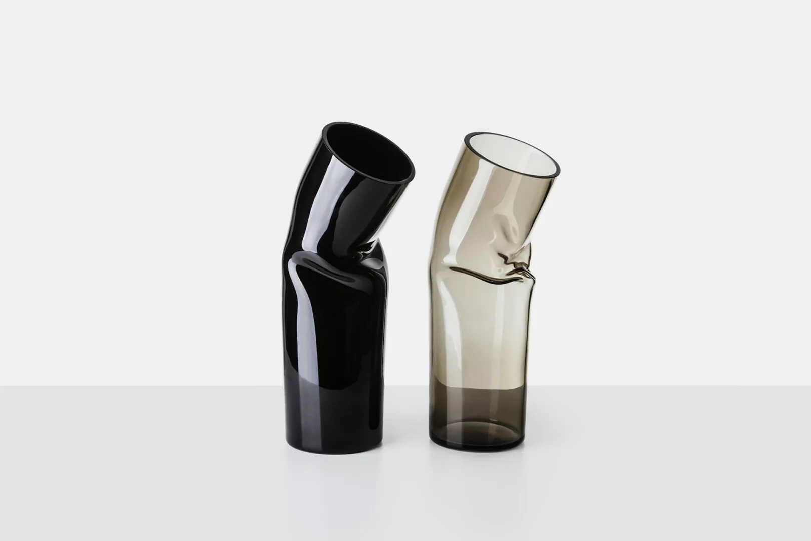 Two twisted glass vases, one black and one beige.
