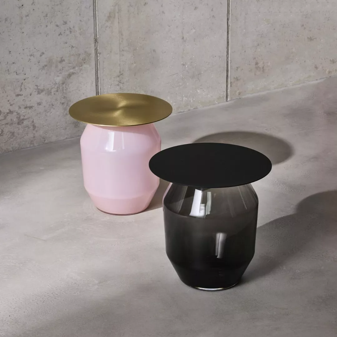 Two modern stools, pink and black, with metallic tops.