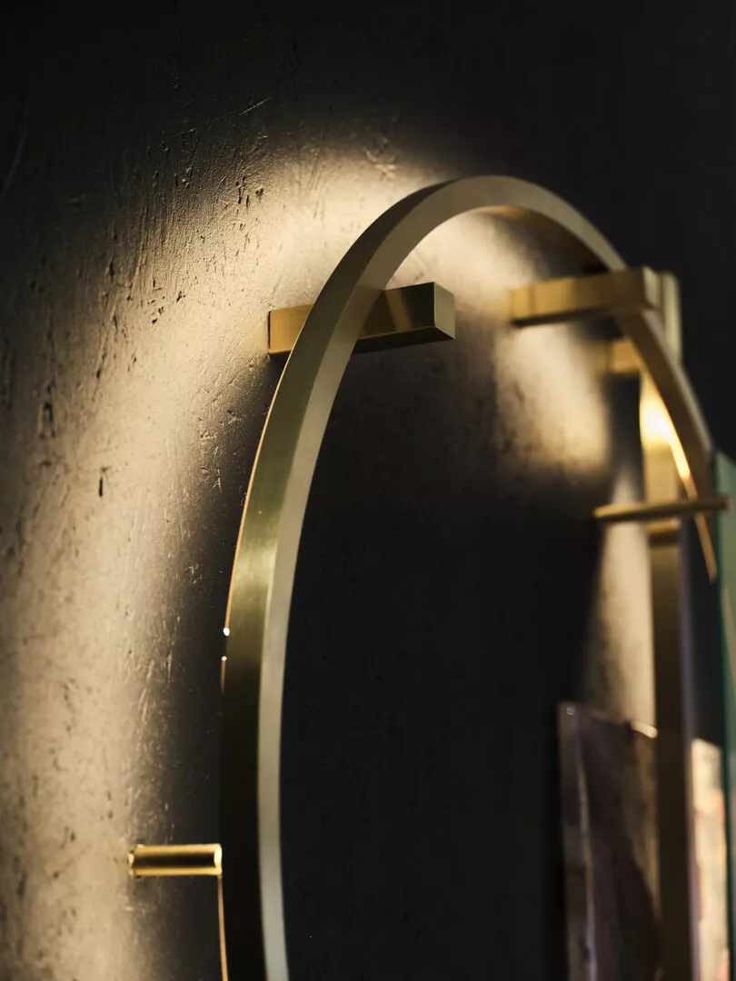 Gold circular shelf on textured dark wall.