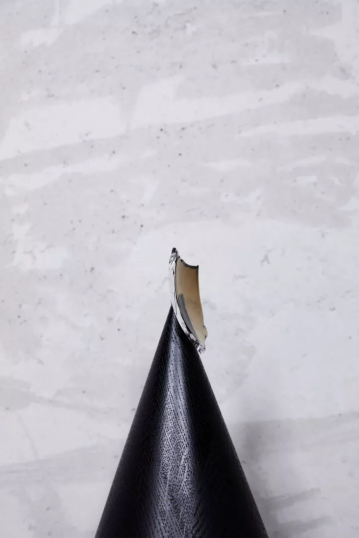 Black cone-shaped object on marbled white surface.