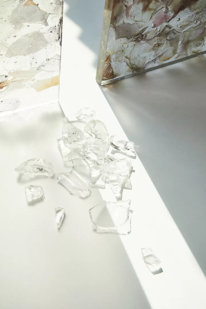 Broken glass shards near artistic resin blocks.