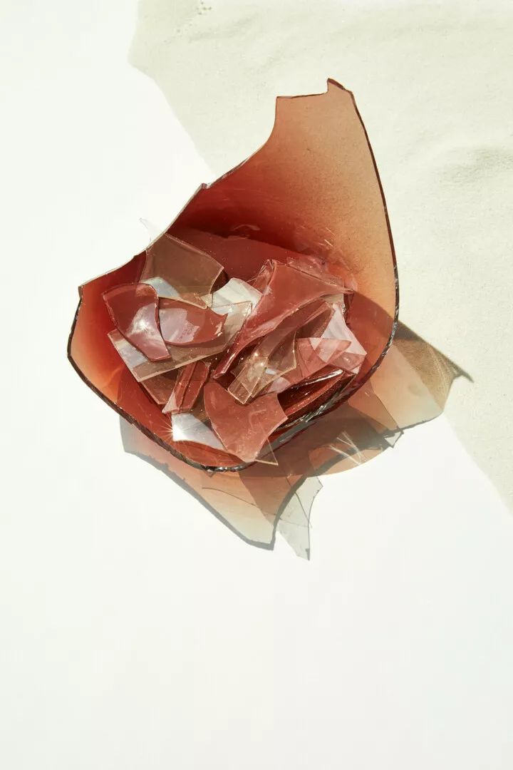 Broken glass pieces in a torn brown paper bag.