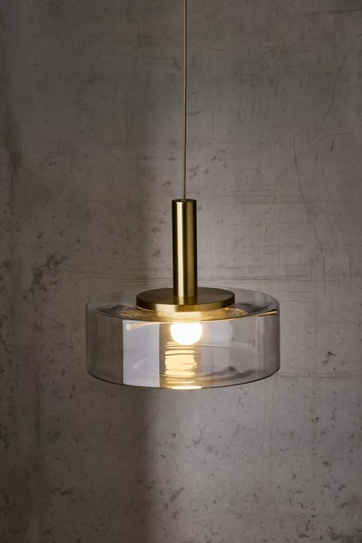 Modern hanging pendant light against textured wall.