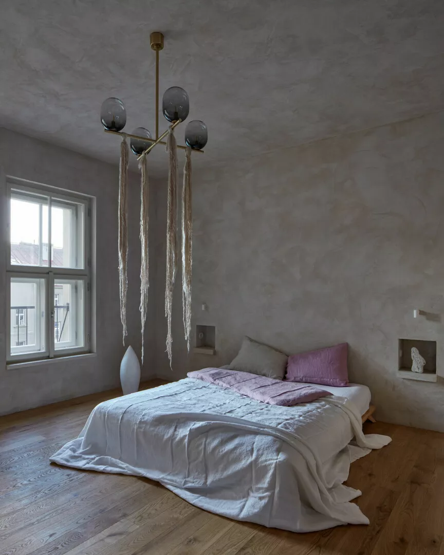 Minimalist bedroom with modern chandelier and wooden floor.
