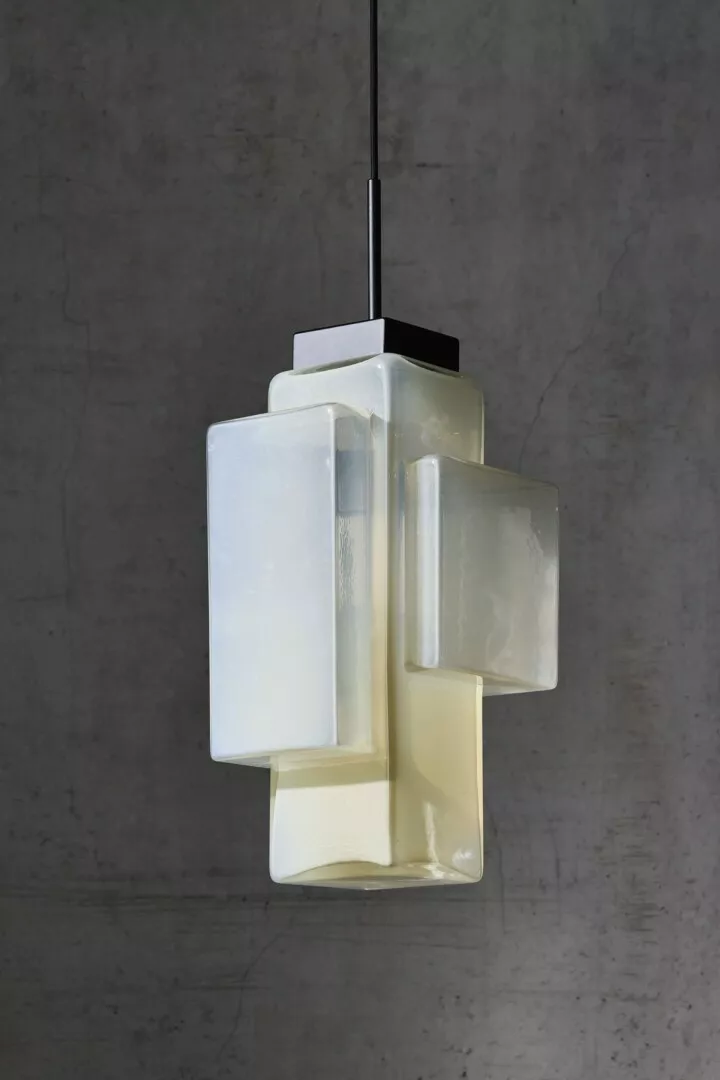 Modern frosted glass pendant light against a concrete wall.