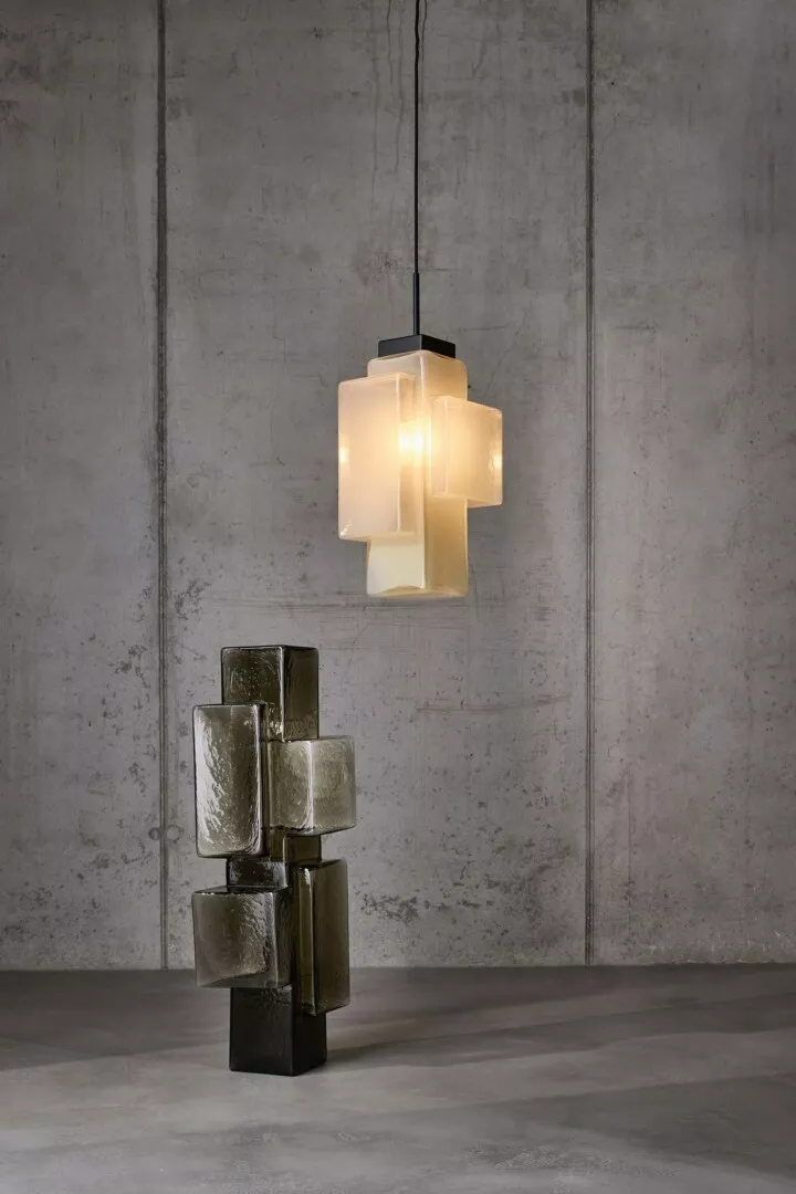 Modern hanging lamp and sculptural glass stack in room.