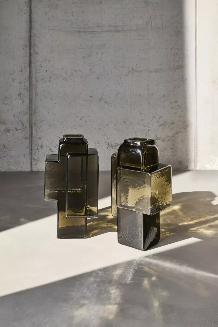Amber glass sculptures in sunlight, gray marble background.
