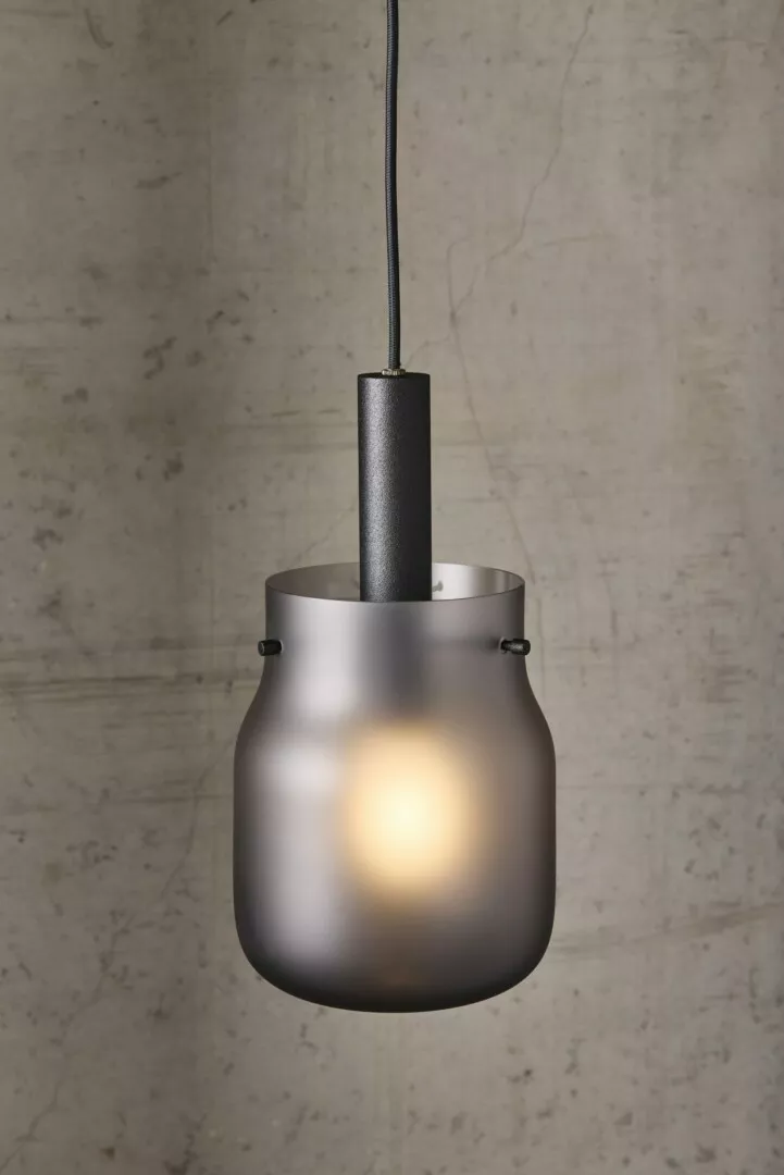Modern frosted glass pendant light against concrete wall.