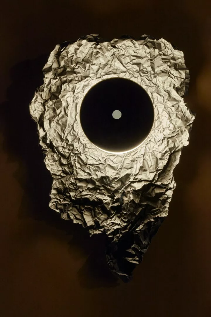 Crumpled paper with circular illuminated cutout.