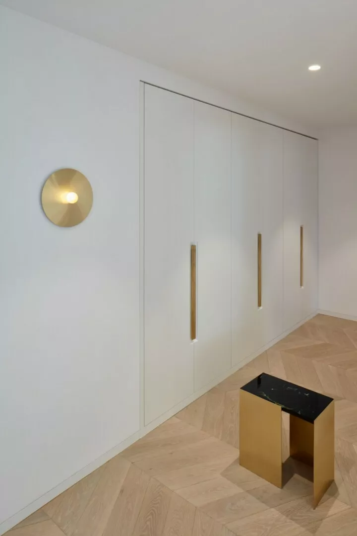 Minimalist hallway with white cabinets and wooden floor.