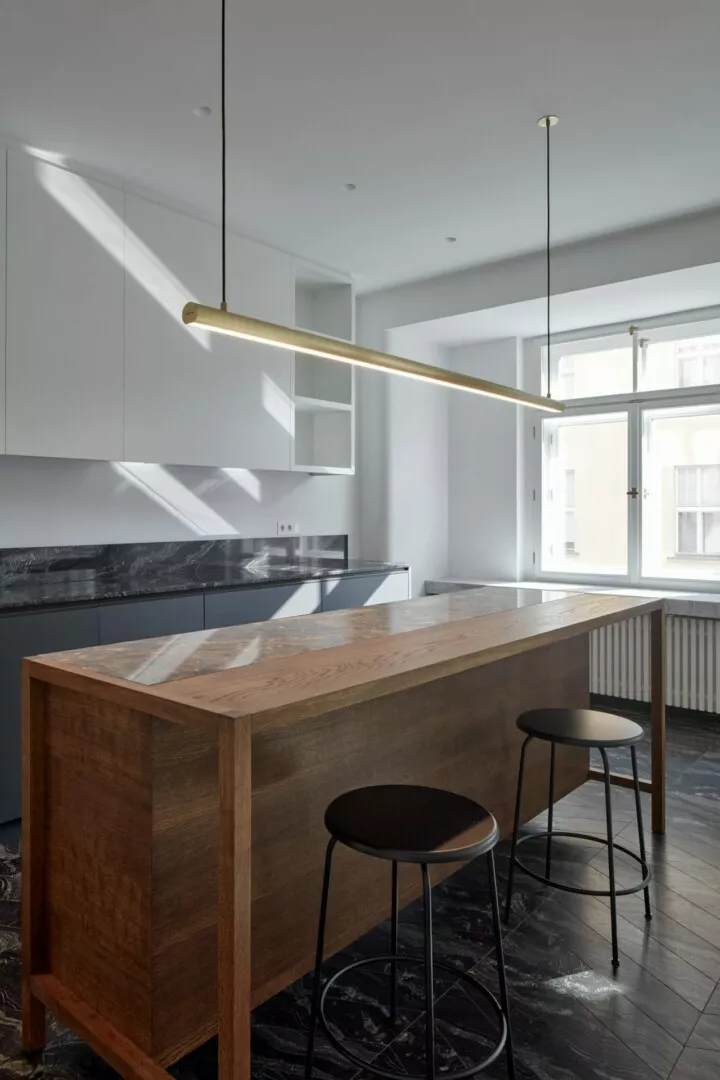 Modern kitchen with wooden island and minimalist lighting.